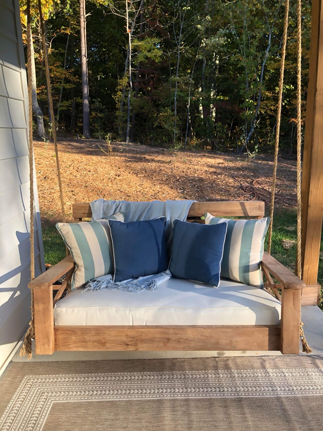 Finished bed swing with striped pillows on a porch in autumn