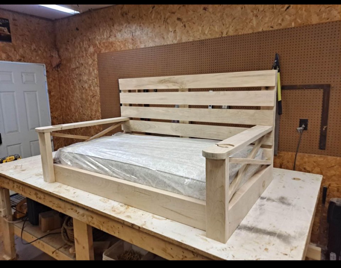 Unfinished bed swing frame with mattress on the workbench