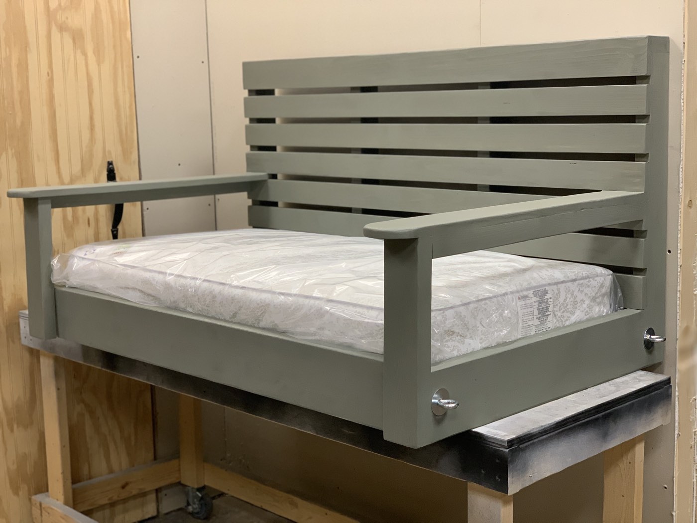 Sage green-painted bed swing frame in the workshop