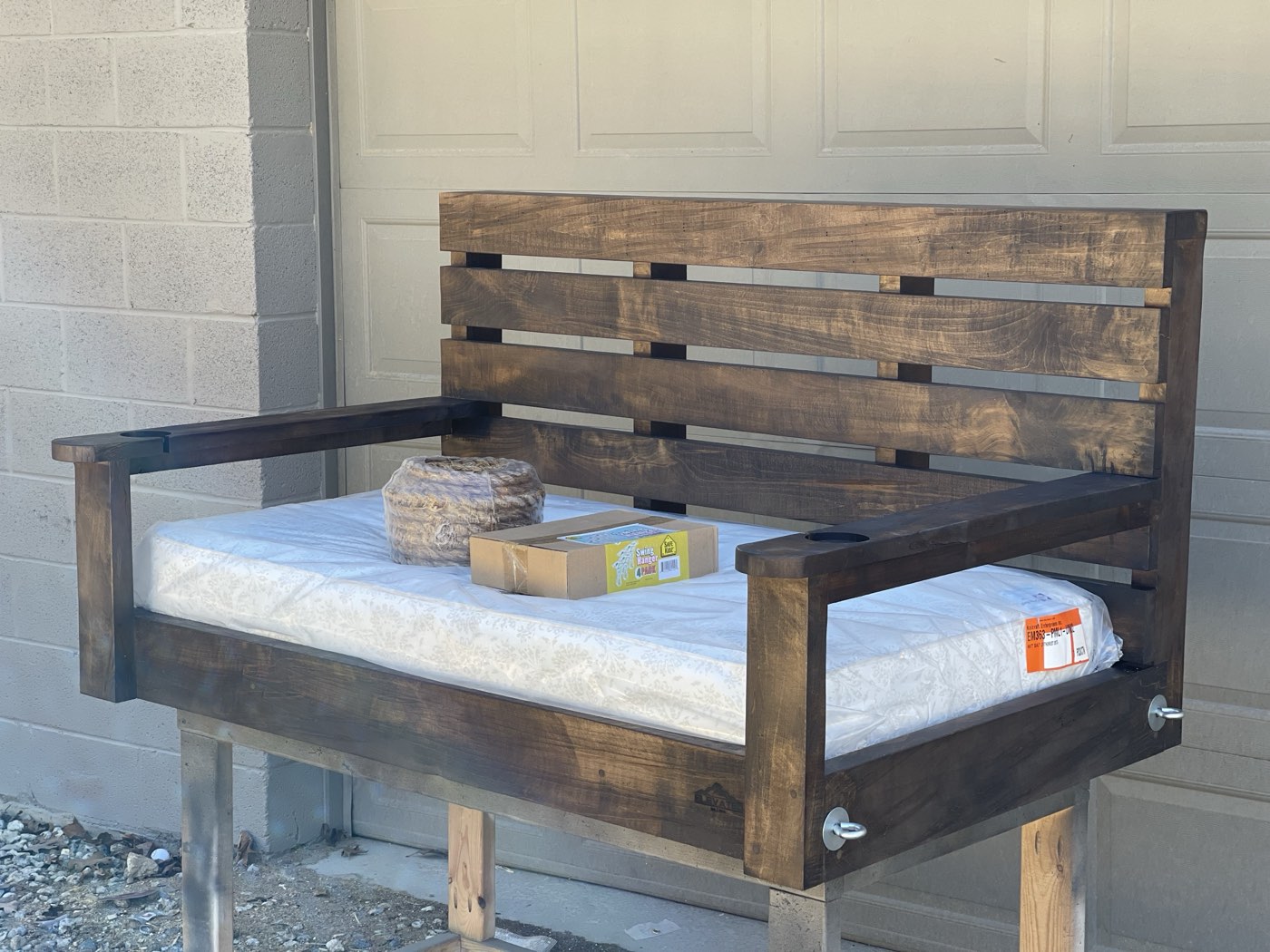 Dark walnut-stained bed swing frame outdoors with hardware